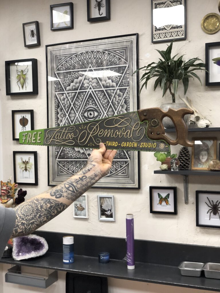 Signpainting op vintage handzaag voor tattooshop
