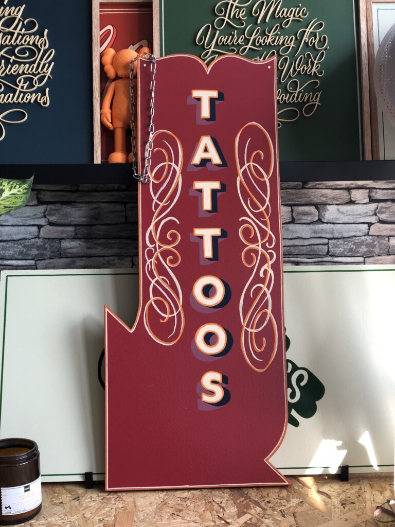 Handgeschilders hang bord voor een tattoo shop