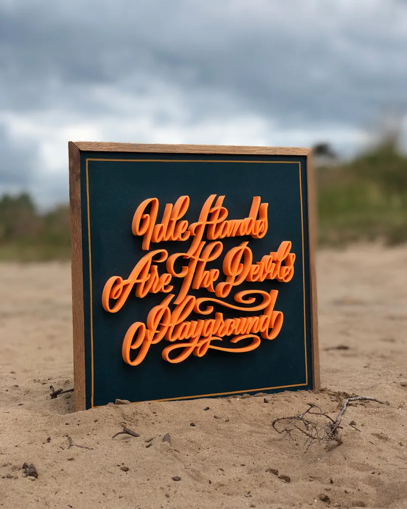Handgemaakte 3D-geprinte kalligrafie met de tekst “Idle Hands Are The Devil’s Playground” op houten bord met hardhouten lijst