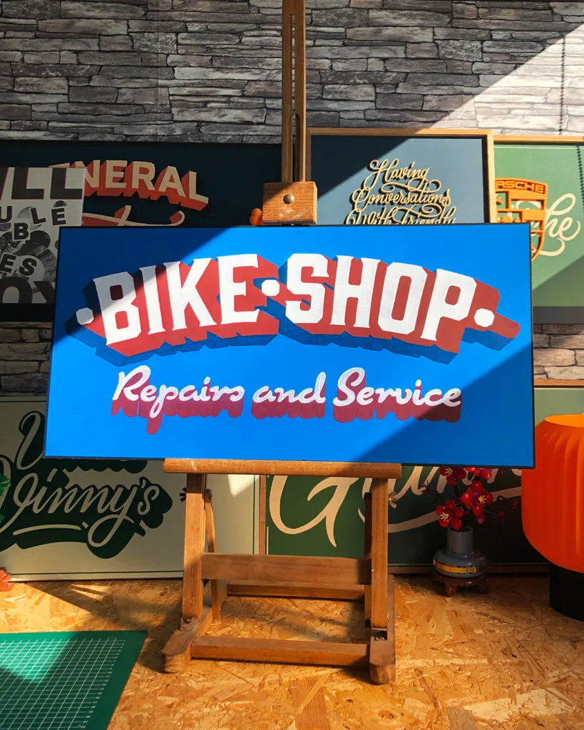 Handgeschilderd reclamebord voor een fietsenwinkel met handgetekende belettering uitgevoerd in traditionele signpainting-stijl.