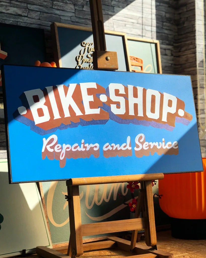 Handgeschilderd reclamebord voor een fietsenwinkel met handgetekende belettering uitgevoerd in traditionele signpainting-stijl.