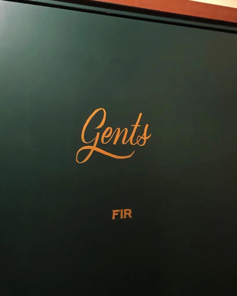 Handgeschilderde gouden scriptbelettering op donkergroene deuren in O' Malley's Irish Pub, uitgevoerd met enamel verf in traditionele signpainting-stijl.